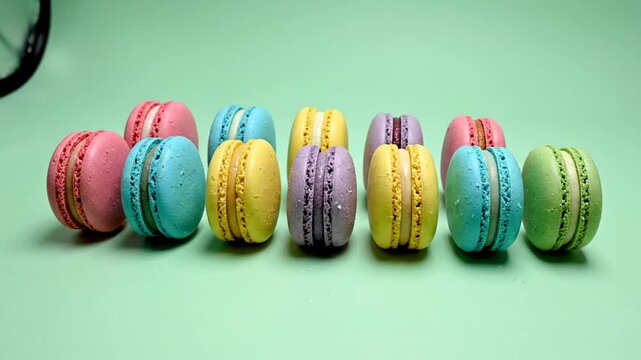 Colorful Macarons Arranged in a Row on a Light Green Surface for a Sweet Dessert Theme