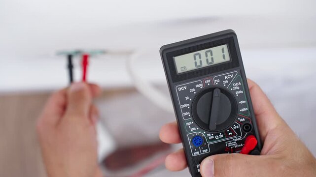Person checking wall outlet voltage with digital multimeter