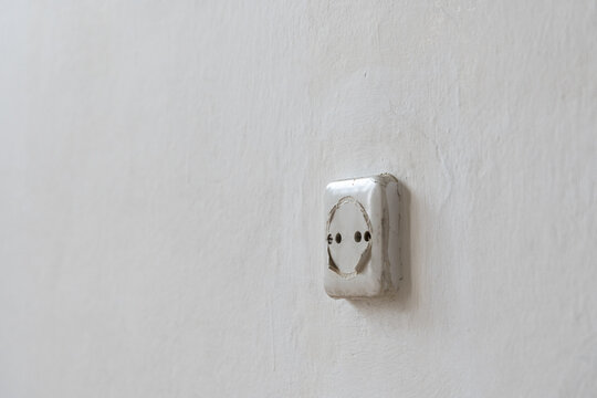 Old apartment interior with outdated electrical outlet on a worn textured wall, poor home condition and residential space requiring renovation