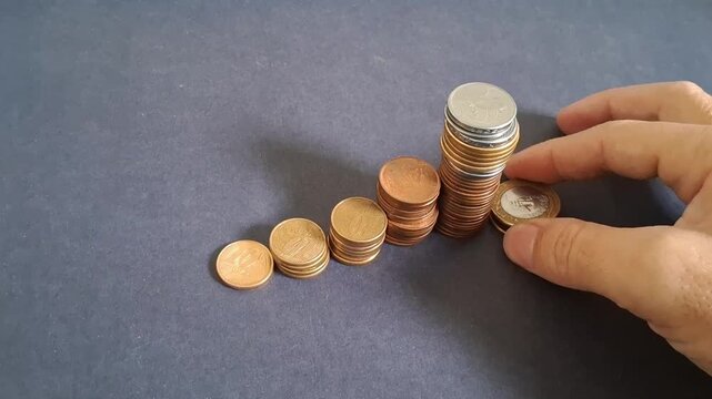 Hand stacking metal coins into growing chart formation