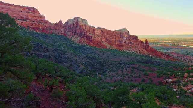 Warm sunset light illuminates Independence Monument and towering sandstone formations along Monument Canyon Loop Trail in Colorado