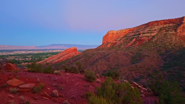 Vast vista reveals the town of Fruita nestled beyond towering red sandstone monoliths along Monument Canyon Loop Trail in Colorado