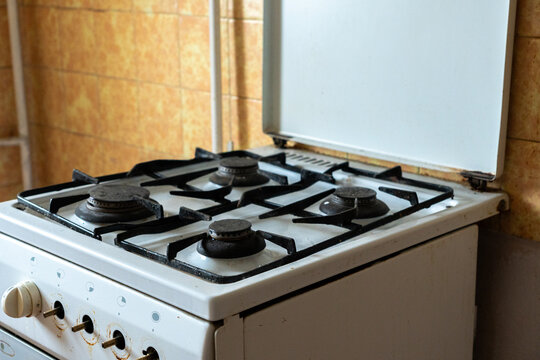 Old gas stove in an outdated apartment kitchen, worn and neglected cooking appliance with stained surfaces, representing a home requiring renovation and refurbishment