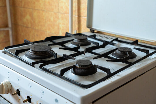 Old gas stove in an outdated apartment kitchen, worn and neglected cooking appliance with stained surfaces, representing a home requiring renovation and refurbishment