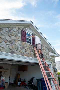 Large ladder leaning on front of stone house over the garage