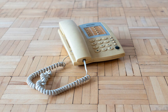 Old apartment interior with outdated landline telephone on worn parquet floor, neglected residential space requiring renovation and home refurbishment