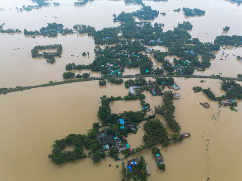 11 July 2026: Aerial view of a flooded rural landscape with houses and trees partially submerged in murky floodwaters.