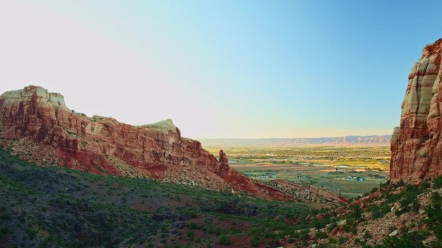 Vast vista reveals the town of Fruita nestled beyond towering red sandstone monoliths along Monument Canyon Loop Trail in Colorado