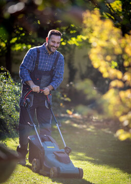 Man mowing lawn in green garden during daytime