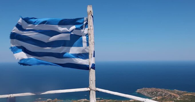 Greek flag flying in the wind high above the Aegean sea on the island of Crete in Greece. 