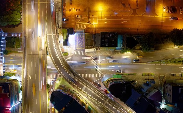 Vertical top down view above the elevated access road of Zhongzheng Bridge and Huanhe Expressway at night, with light trails of cars dashing on the highways in Yonghe District, New Taipei City, Taiwan