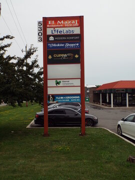 Gloucester, Ontario, Canada &ndash; July 12, 2026: An outdoor view showing a tall commercial directory pylon sign listing multiple businesses including "El Mazaj, LifeLabs, and TLC Grooming" on Canotek Road