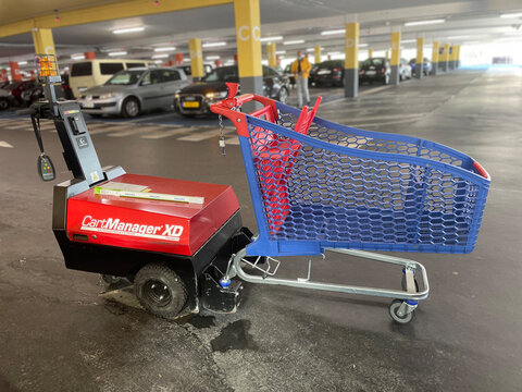 annecy, France - September 30 2021: Red CartManager XD machine connected to a blue shopping cart in an Annecy, France, parking garage.