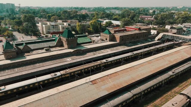 Aerial drone view of passenger train carriages parked along platform sheds at historic Rawalpindi Railway Station in Pakistan.