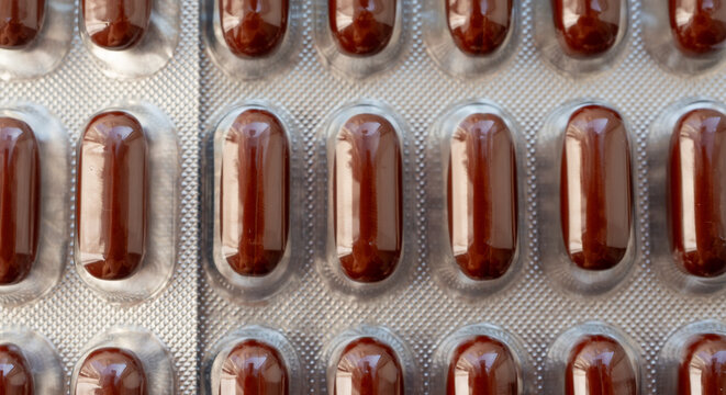 Brown gel pills, dark red capsules close up