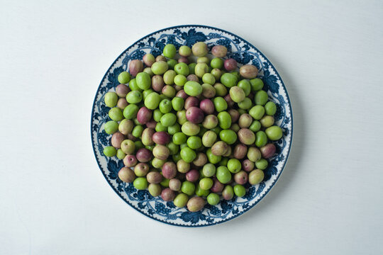 Fresh green and purple olives on a decorative ceramic plate