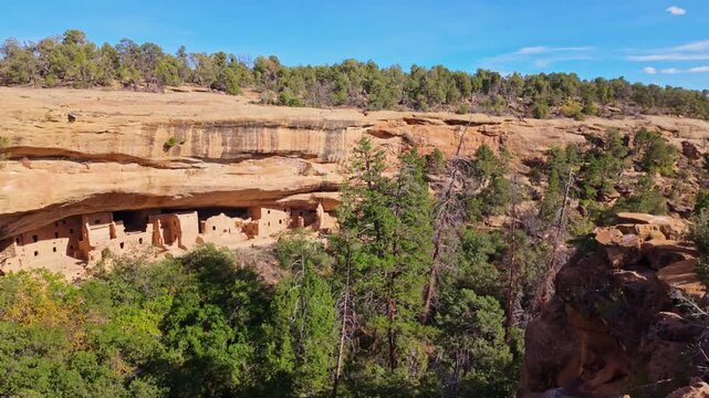 Golden sunset light bathes ancient preserved sandstone masonry structures sheltered within the giant natural alcove of Spruce Tree House