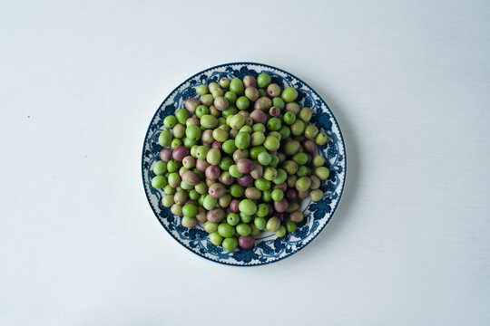 Fresh green and purple olives on a decorative ceramic plate