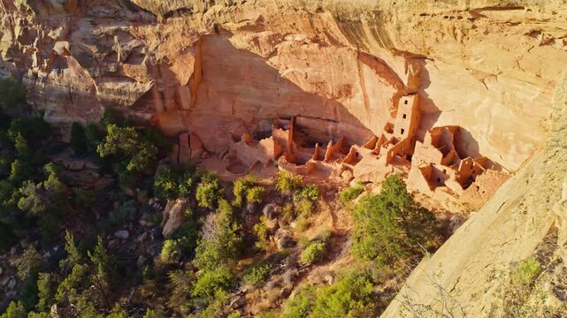 Golden sunset light illuminates the tall sandstone masonry tower and alcove rooms at Square Tower House in Mesa Verde National Park