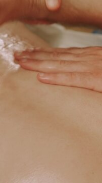 extreme close view of hand pressing and gliding oil over moisturized skin, glossy texture and soft highlights