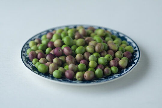 Fresh green and purple olives on a decorative ceramic plate