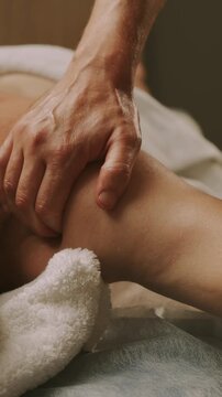 closeup therapist hand compressing outer thigh muscle with firmly touch during massage in warm treatment room