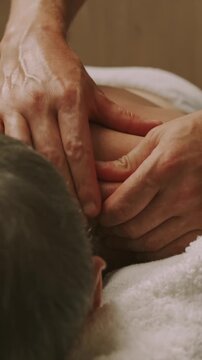 close-up of therapist thumbs and fingers kneading neck and upper shoulder with calming pressure during session