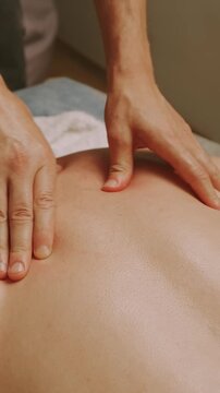 close-up view of therapist hands pressing and gliding over upper back on massage table, promoting comfort