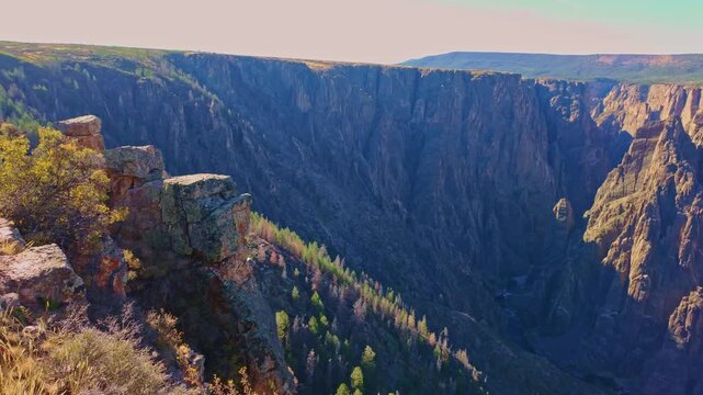 Warm evening light illuminates the sheer dark Precambrian walls and deep gorge of Black Canyon of the Gunnison National Park Colorado