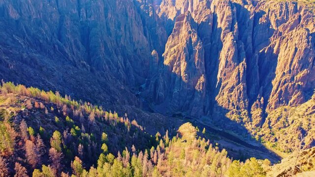 Warm evening light illuminates the sheer dark Precambrian walls and deep gorge of Black Canyon of the Gunnison National Park Colorado