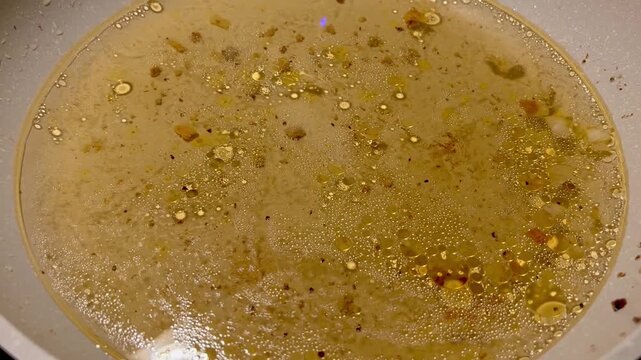 Dirty cooking oil moving in a frying pan on a stovetop
