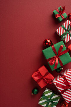 Merry Christmas and Happy New Year with red and green wrapped gifts and ornaments on vertical maroon copyspace