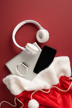 Santa Claus present bag with headphone, phone and smartwatch for Merry Christmas and Happy New Year on vertical burgundy backdrop
