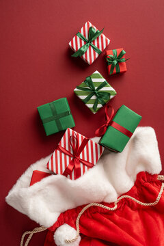 Merry Christmas and Happy New Year with Santa Claus presents in festive red and green wrapping on vertical maroon background