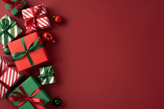 Festive red and green Christmas presents with ribbons and ornaments on a flat holiday background