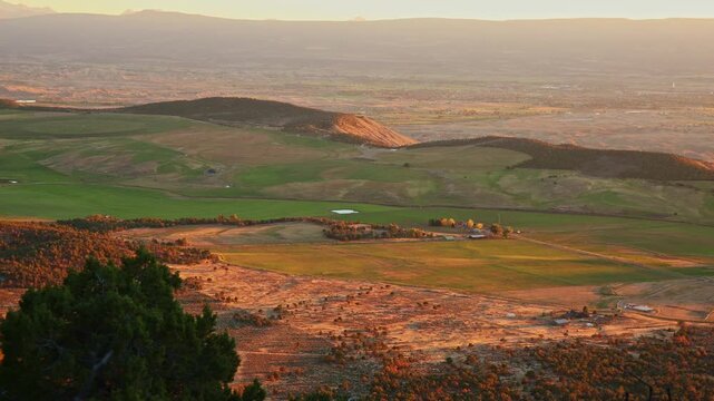 Warm evening sunlight illuminates lush farmland valleys and distant mountain ranges from Warner Point trail in Colorado