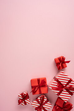 Red gift boxes with ribbons on pink background for Merry Christmas and Happy New Year celebrationon vertical pastel pink background