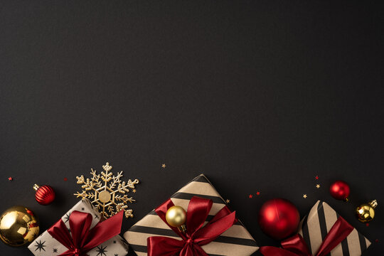 Christmas gifts with red ribbons and gold ornaments on a black background for Merry New Year celebration