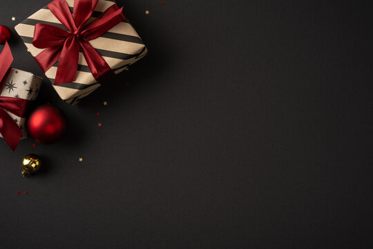Elegant Christmas presents with red ribbons and baubles on black background for New Year greeting