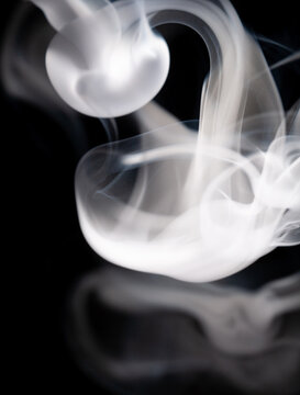 Smoke rises and swirls against a black background creating unique shapes and patterns