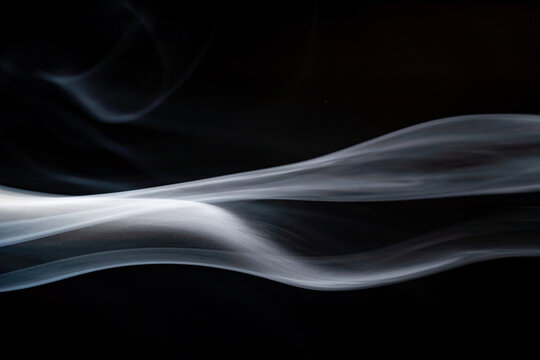 Swirling white smoke against a black background displaying smooth curves and flowing patterns