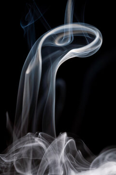 Smoke rises and swirls against a black background creating unique shapes and patterns