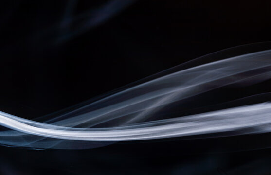Swirling white smoke against a black background displaying smooth curves and flowing patterns
