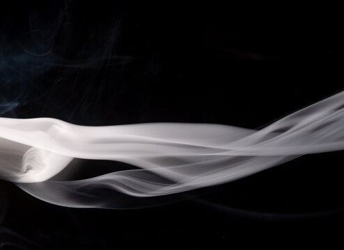 Swirling white smoke against a black background displaying smooth curves and flowing patterns