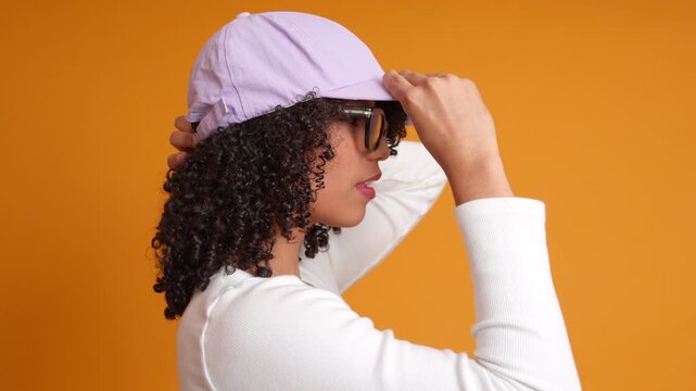 Young happy woman putting on a baseball cap in slow motion