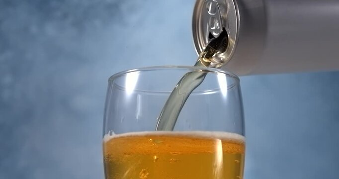 Beer pouring from aluminum can into glass in super slow motion