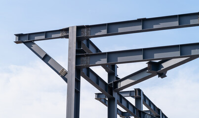 Obraz premium Close-up of a bolted steel frame joint with H-beams, columns and diagonal braces. Structural steel framework for an industrial building with beams, columns and support elements.