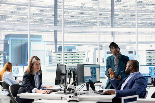 Technicians working together in microchip manufacturing factory office, conducting RD study on SoC architecture design, african american coworkers develop innovative semiconductors technology.
