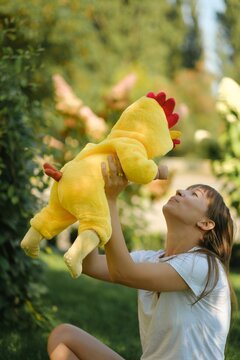 Happy mother holding cute baby in yellow chicken costume outdoors in park on sunny day