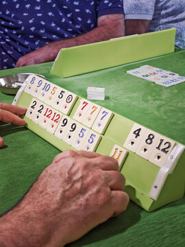 Hands of Elderly People Playing Traditional Okey Tile Game on Green Table